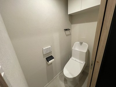 【トイレ】清潔に利用できる温水洗浄機能付きトイレです。上部には収納棚が設置されており、トイレットペーパーや掃除用品を収納することができます。