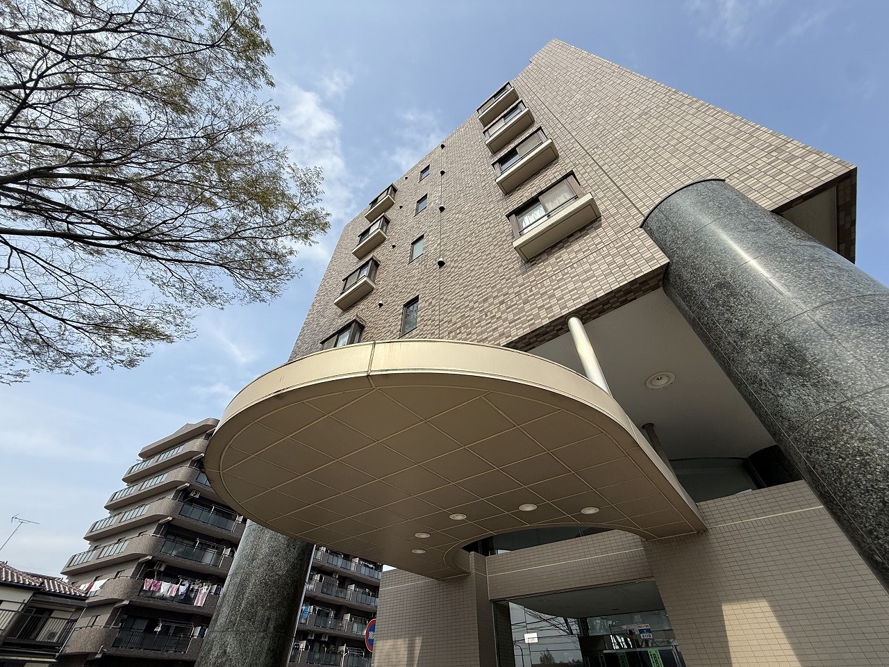 【現地外観写真】緑豊かな住宅地に位置する、鉄筋コンクリート造8階建・総戸数89戸のマンション。駅までの道のりは平坦なので、自転車や徒歩での移動もしやすいです。