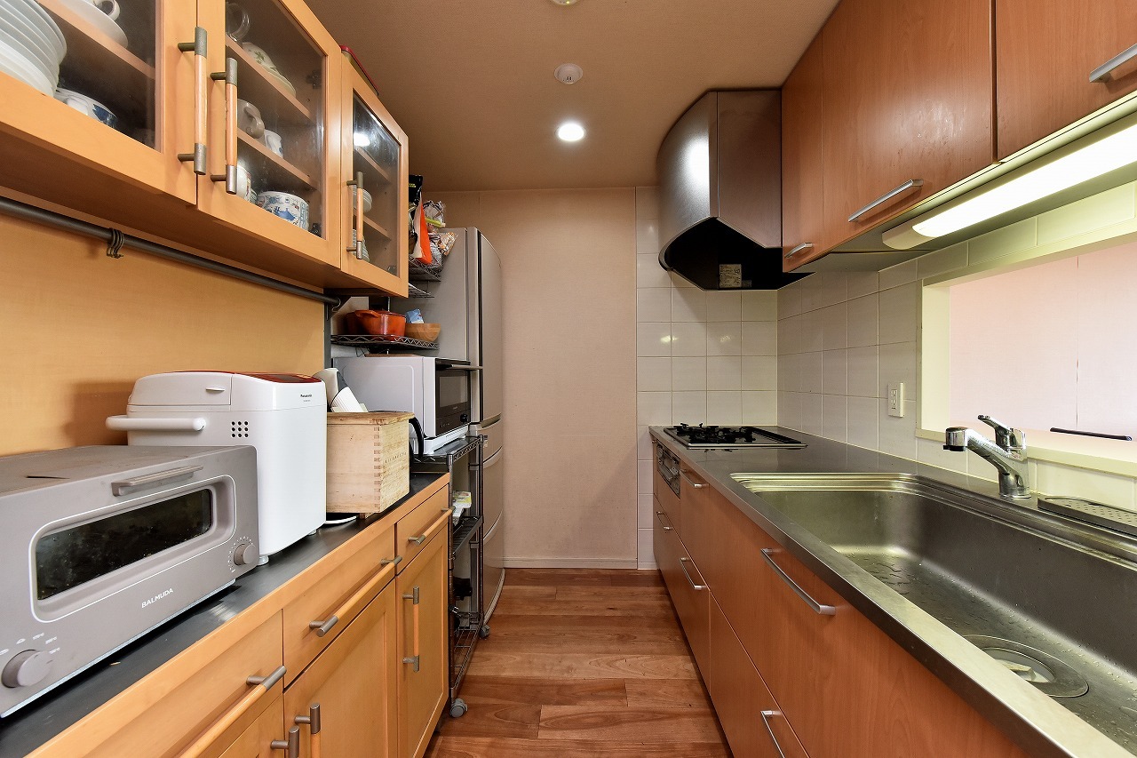 【キッチン】上下に豊富な収納スペースが備わったシステムキッチン。調理家電や食器類をすっきりと整理でき、隣接する納戸はパントリーとしても活用可能です。