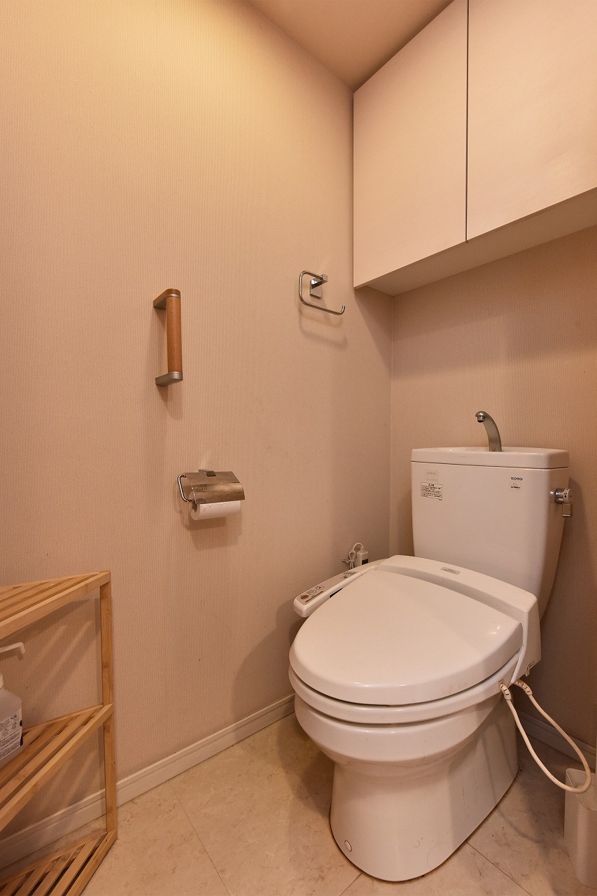 【トイレ】背面上部に扉付きの吊戸棚が設置されています。トイレットペーパーや洗剤などのストック品を隠して収納できます。