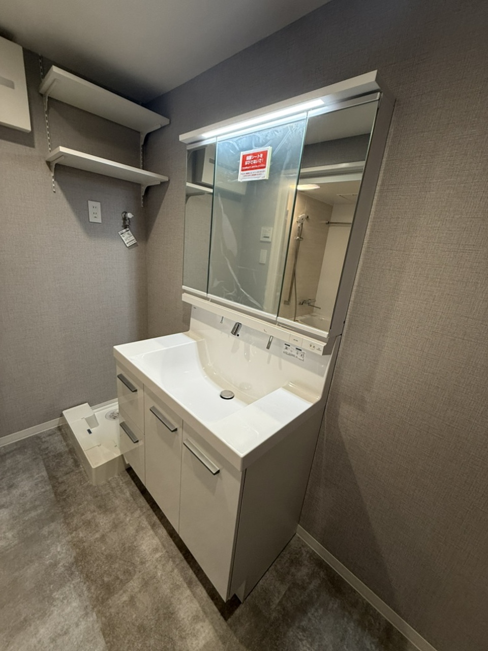 【洗面室】洗濯パンが設置されており、上部には可動式の棚が備わっています。洗剤などのストック置き場に重宝しそうです。