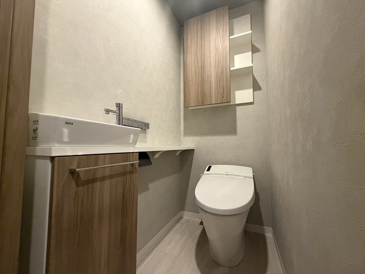 【トイレ】清潔に利用できる温水洗浄機能付きトイレです。背面と手洗い器下部に収納スペースがあり、トイレットペーパーや掃除用品を収納することができます。