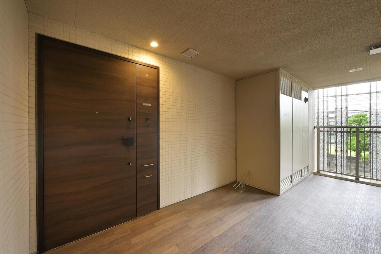 【玄関】木目調の美しい玄関扉が、居住者や来訪者を出迎えてくれます。玄関前には専用の自転車置き場を備えています。