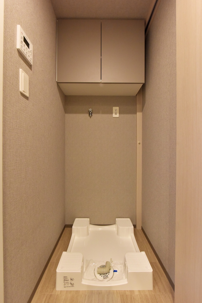 【洗濯機置き場】掃除道具や洗濯用品を収納できる吊戸棚付き。洗濯防水パンは、洗濯機下の掃除がしやすいかさ上げタイプが採用されています。