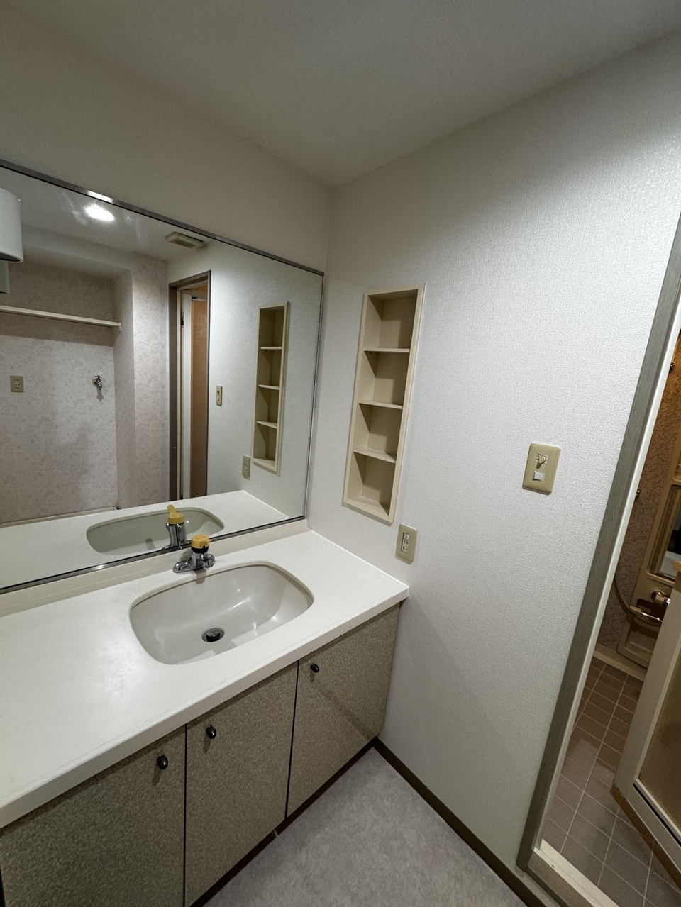 【洗面室】大きな鏡付きの洗面化粧台で、朝の身支度もスムーズに行えます。ボウル下や壁面の収納に加えて広めのカウンターがあり、タオルやスキンケア用品もすっきり整理できます。