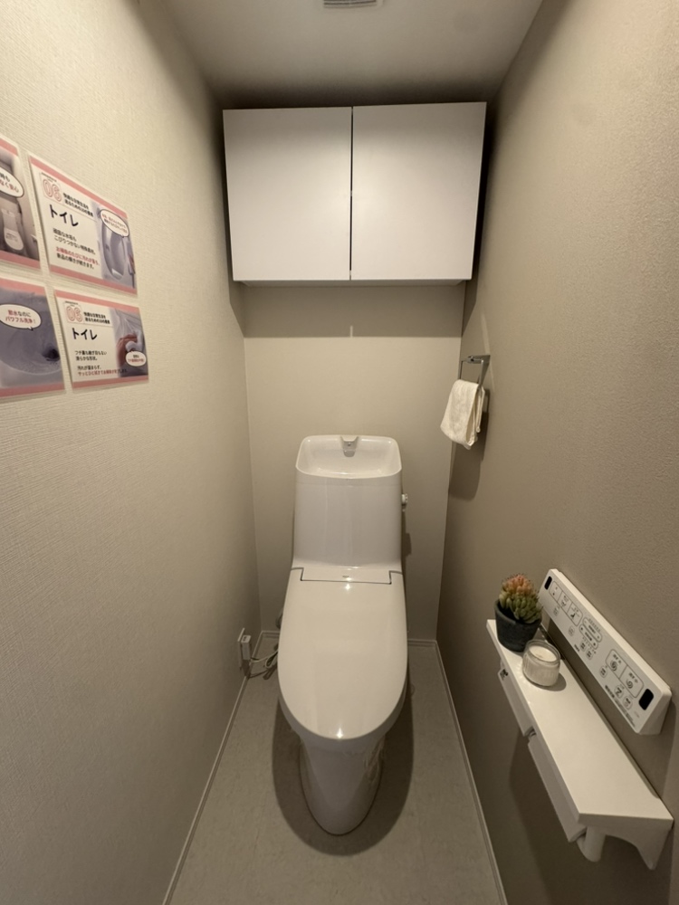 【トイレ】年間を通じて快適にご使用いただける、温水洗浄便座付きのトイレです。背面に吊戸棚があり、トイレットペーパーなどを収納できます。