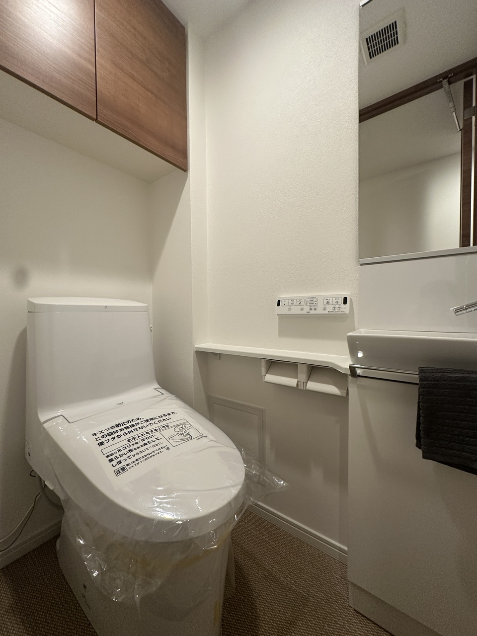 【トイレ】清潔に利用できる温水洗浄機能付きトイレです。上部には収納棚が設置されており、トイレットペーパーや掃除用品を収納することができます。