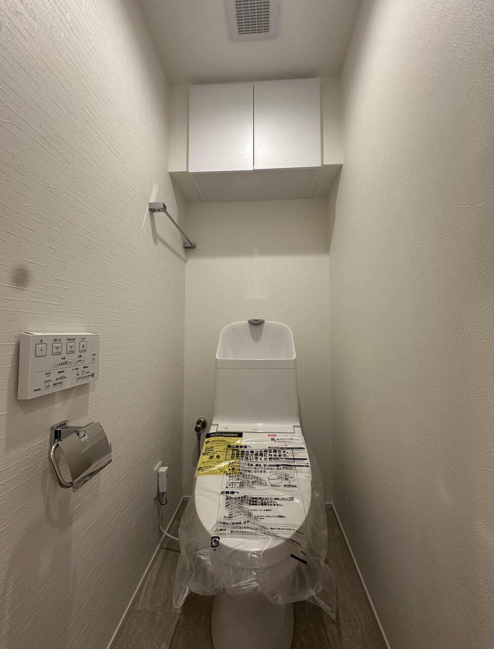 清潔感あふれる新規交換済みの温水洗浄便座付きトイレ。トイレットペーパー等をしまえる上部吊戸棚付き。