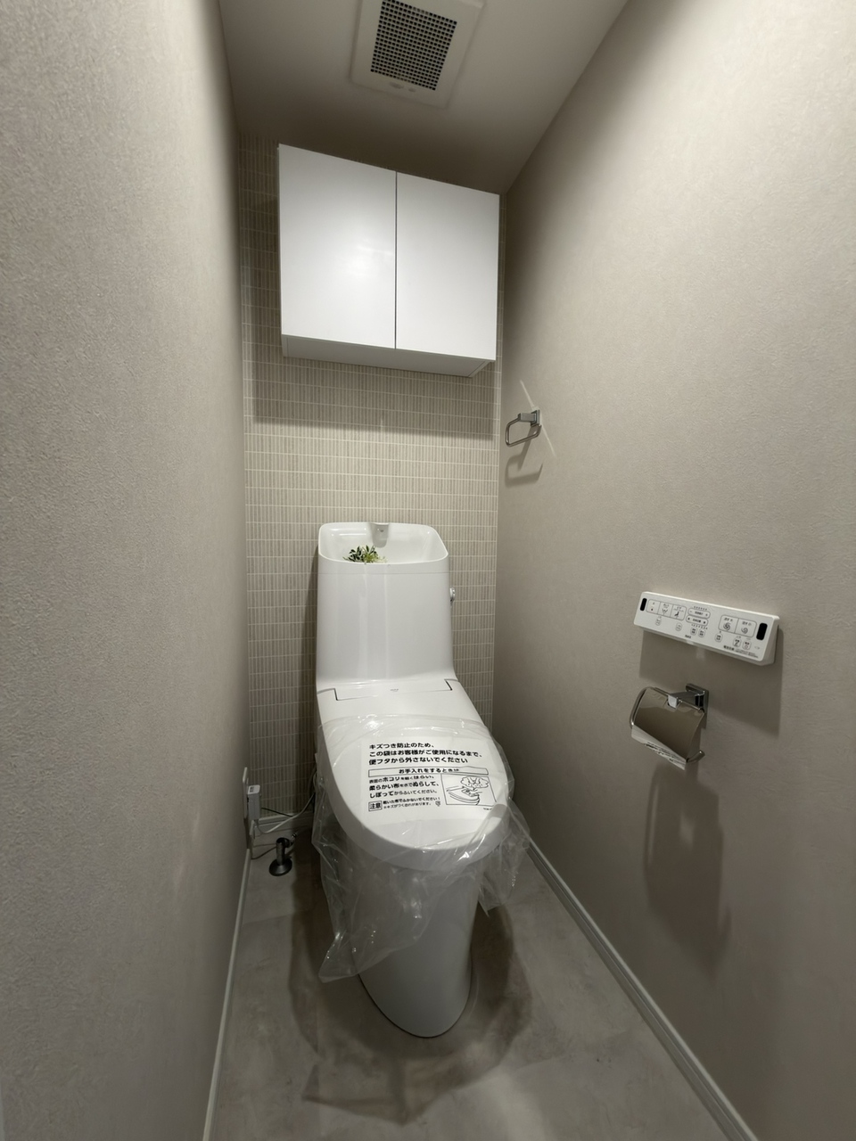 【トイレ】アクセントクロスが施された、温水洗浄便座付きのトイレ。上部に収納棚が有り、トイレットペーパーや掃除用品を収納することができます。