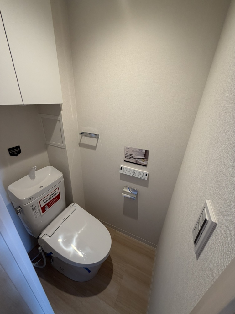 【トイレ】手洗い器一体型、温水洗浄便座付きのトイレ。吊戸棚が設置され、トイレットペーパーなどのストックが可能です。