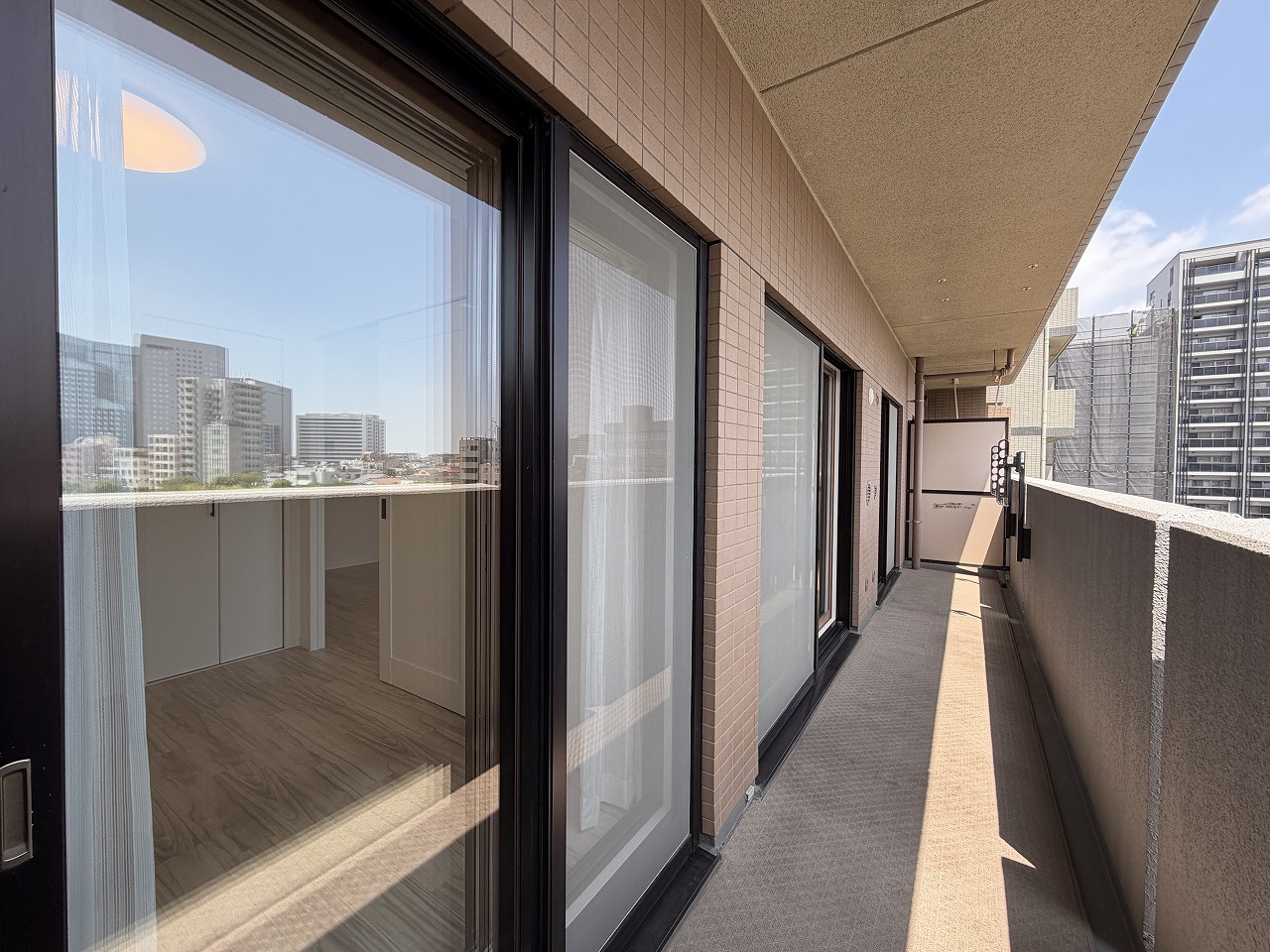 【バルコニー】LDKと洋室2部屋に跨った、横幅のあるバルコニー。折り畳みできる物干し金物が設置されています。屋根があり、少しの雨では洗濯物が濡れにくいです。