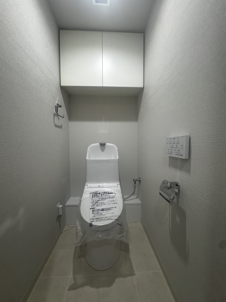 【トイレ】1年を通して快適にご使用いただける温水洗浄便座付のトイレです。背面に吊り戸棚があり、トイレットペーパーや掃除用具の保管にご活用いただけます。