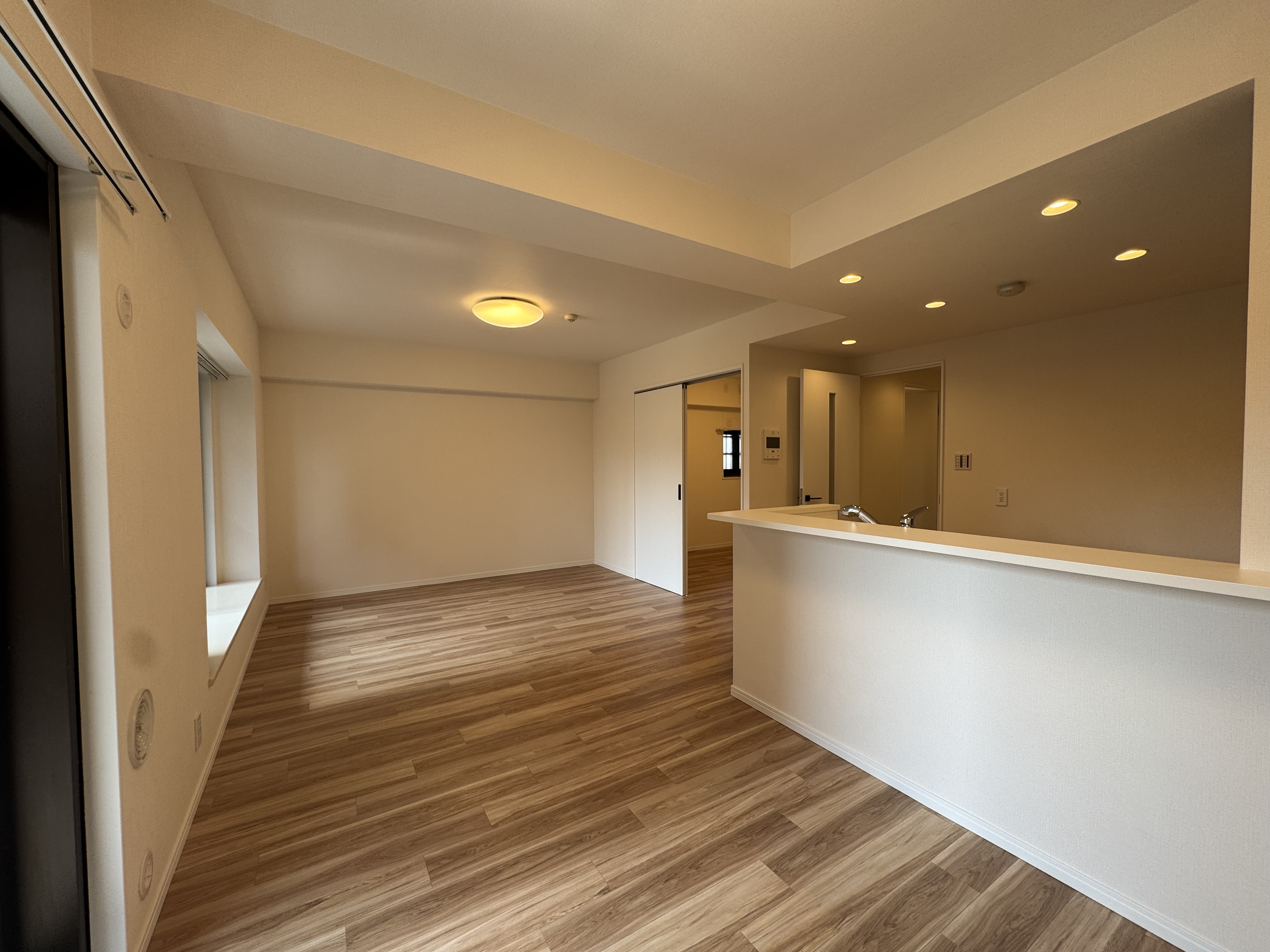 【LDK】隣接する約5.0帖の洋室を開放すると、21帖超の広々とした空間に。キッチンは、リビングやダイニングで過ごすご家族に目が届きやすい対面式です。/2026年3月クロス・フローリング張替済み