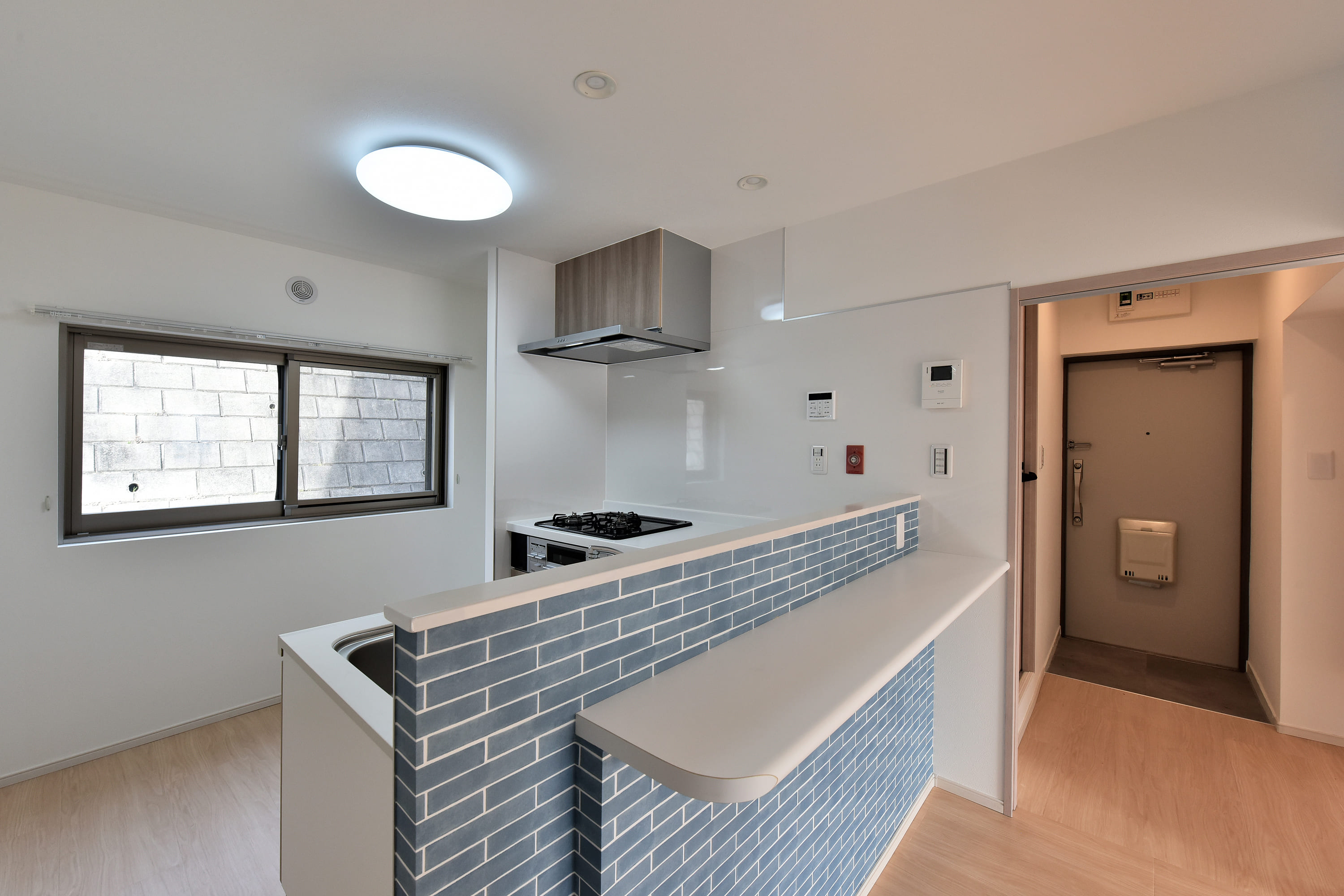 【キッチン】キッチン前面に腰壁が施されているので、手元が見えにくく、シンクが散らかっていても気になりにくい仕様です。コンロ横に窓があるので、換気の際に役立ちます。