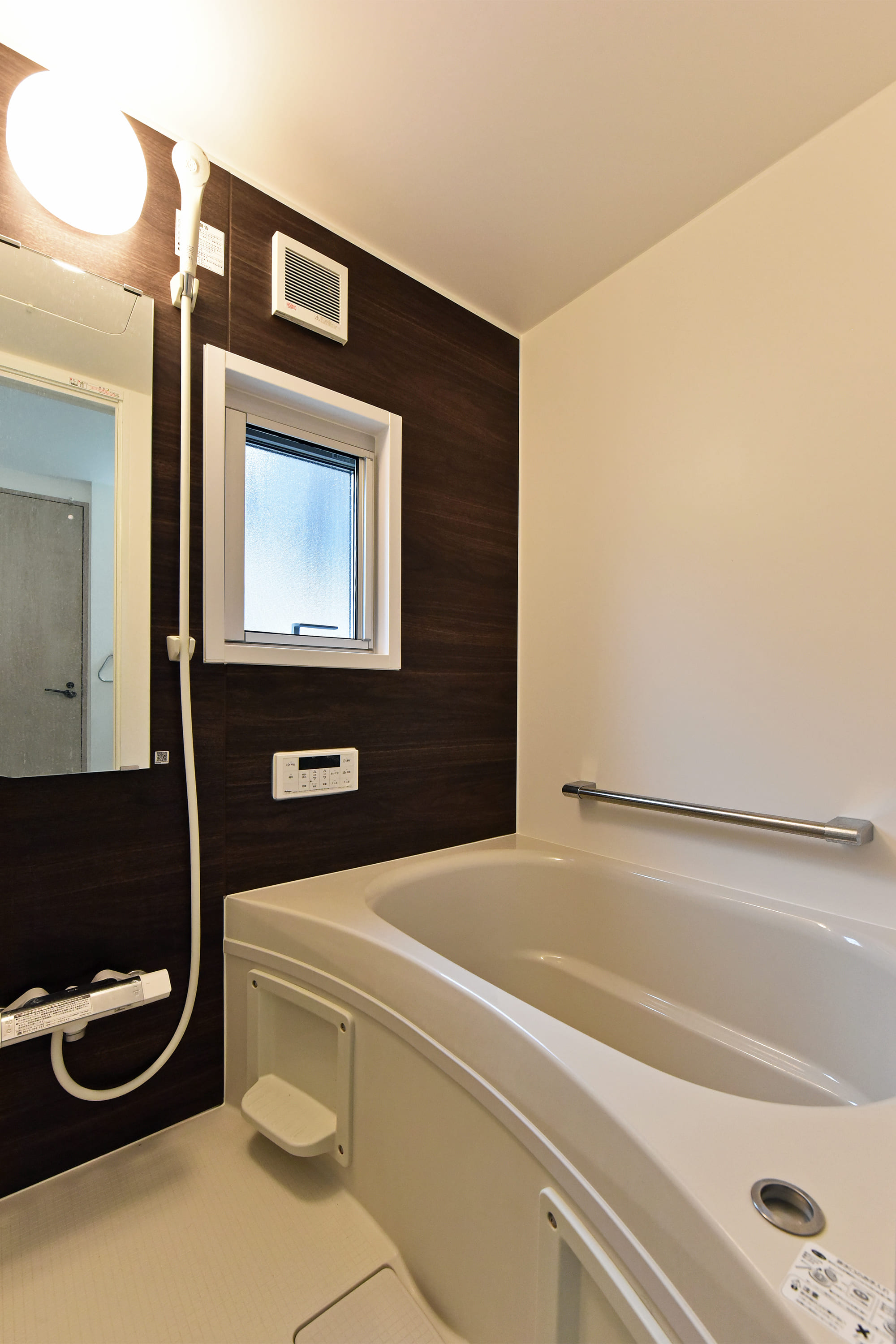 【浴室】木目調のアクセントパネルが施された、落ち着いた雰囲気の浴室。シャワー用スライドバーが採用されています。窓付きなので、自然換気がしやすいです。