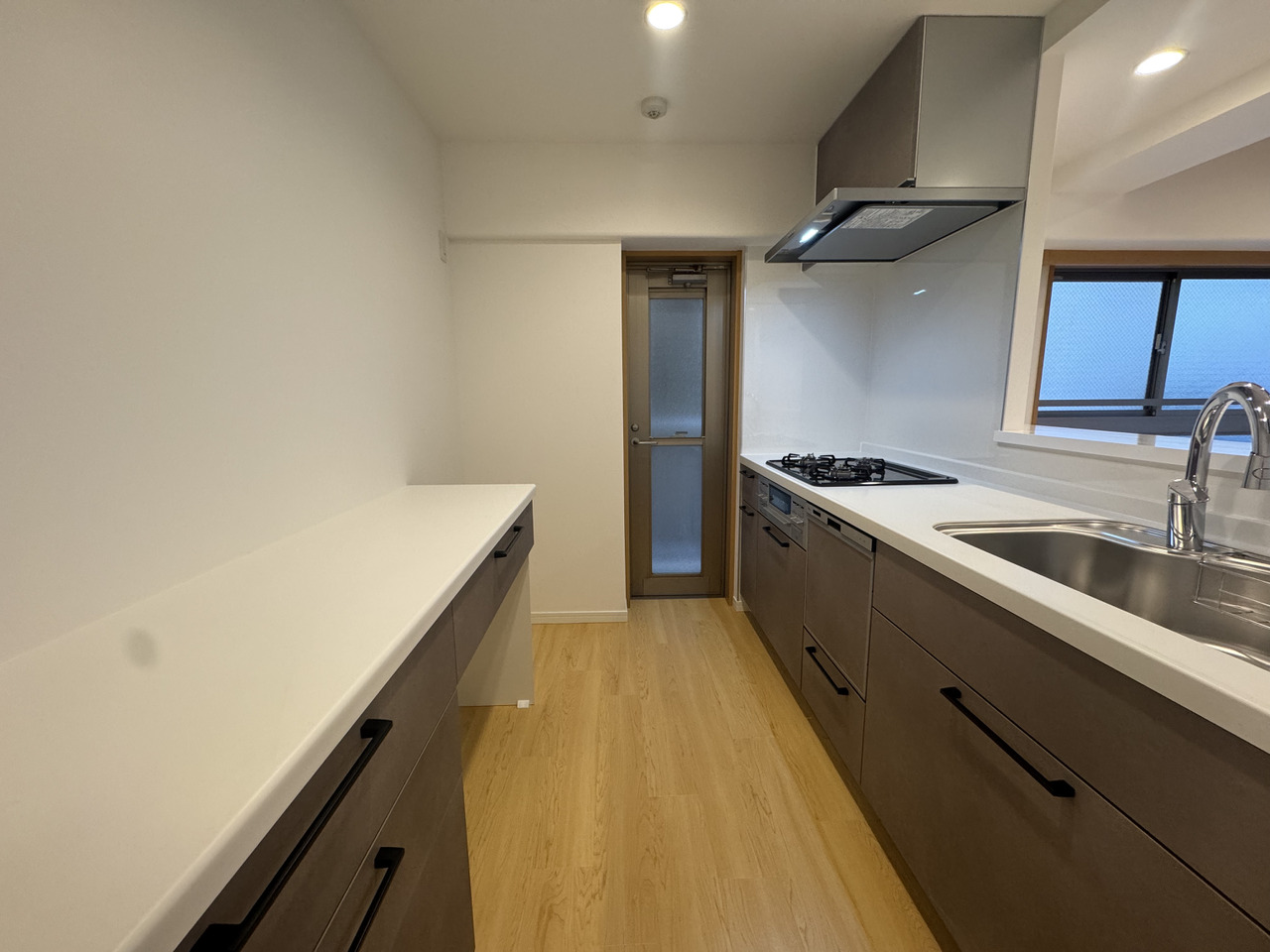 【キッチン】背面にはキッチンと色味が揃ったカップボードが備わっています。調理家電や食器類をすっきりと整理できます。勝手口があり、調理中の匂い・煙対策の換気も十分に行えます。