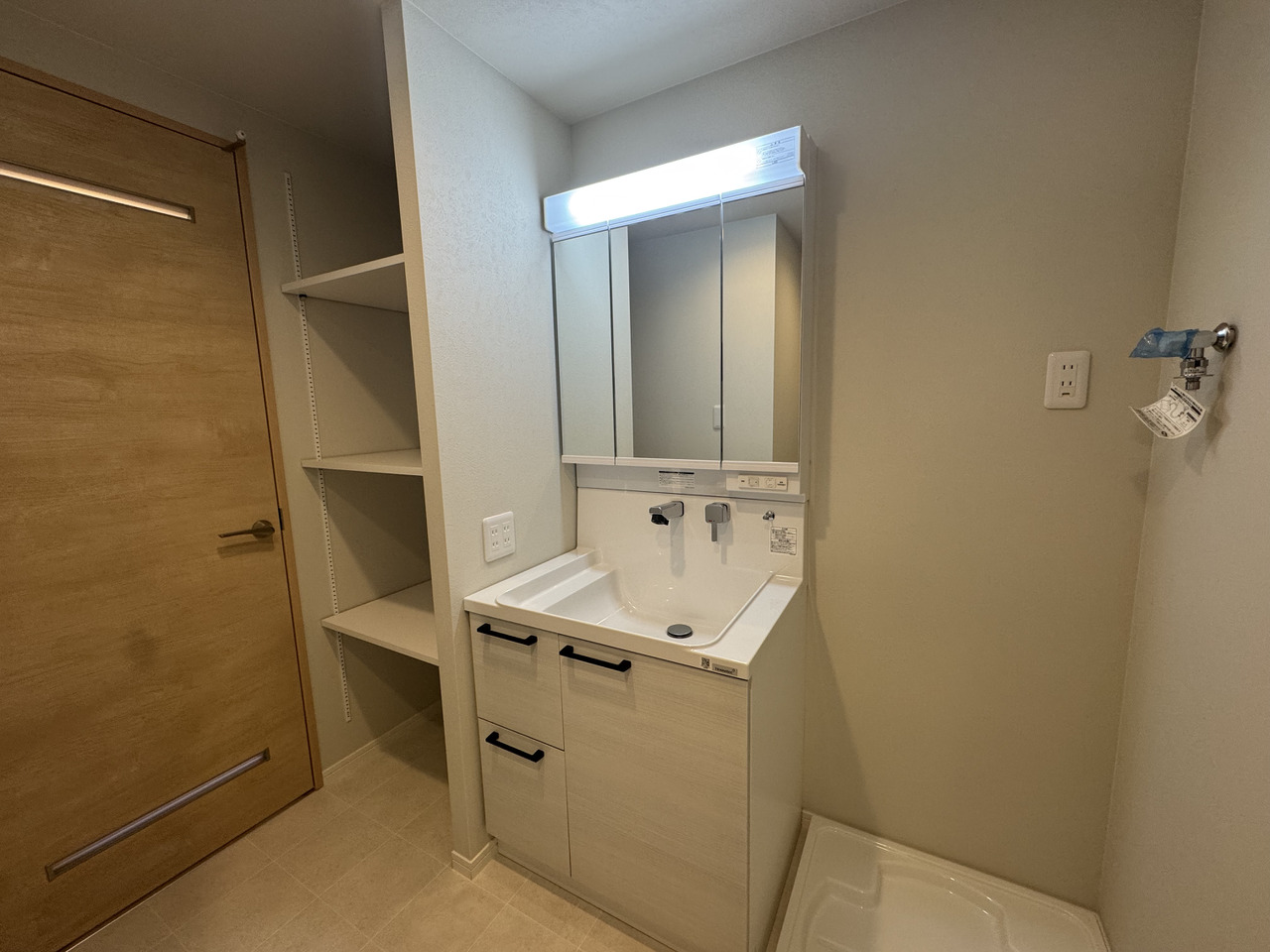 【洗面室】化粧品や小物類などをすっきりと収納できる、三面鏡付きの洗面台が備わっています。可動棚が採用された物入もあり、収納豊富です。