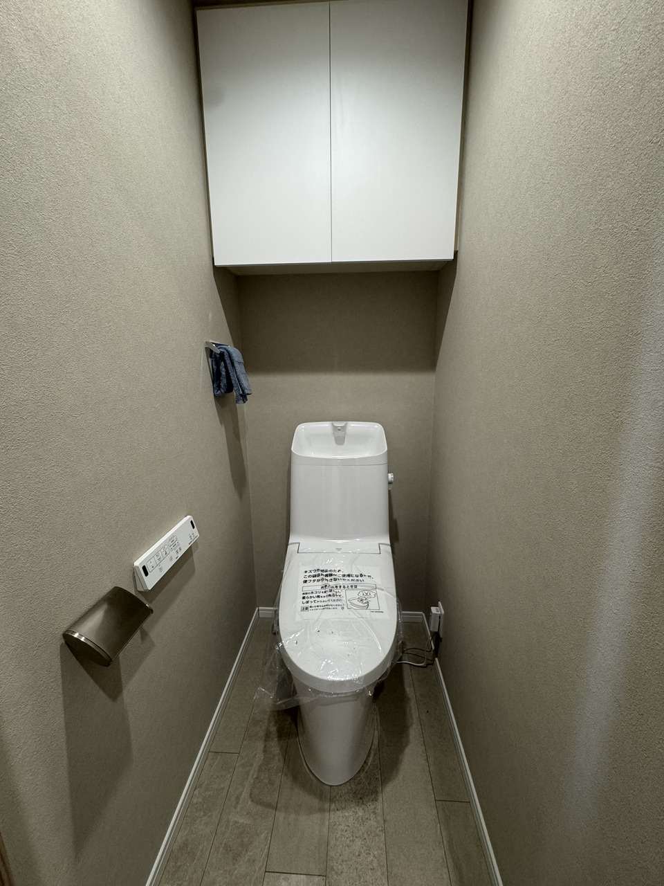 【トイレ】1年を通して快適にご使用いただける、温水洗浄便座付きのトイレです。背面に吊り戸棚があり、掃除用具の保管やトイレットペーパーのストックに重宝します。