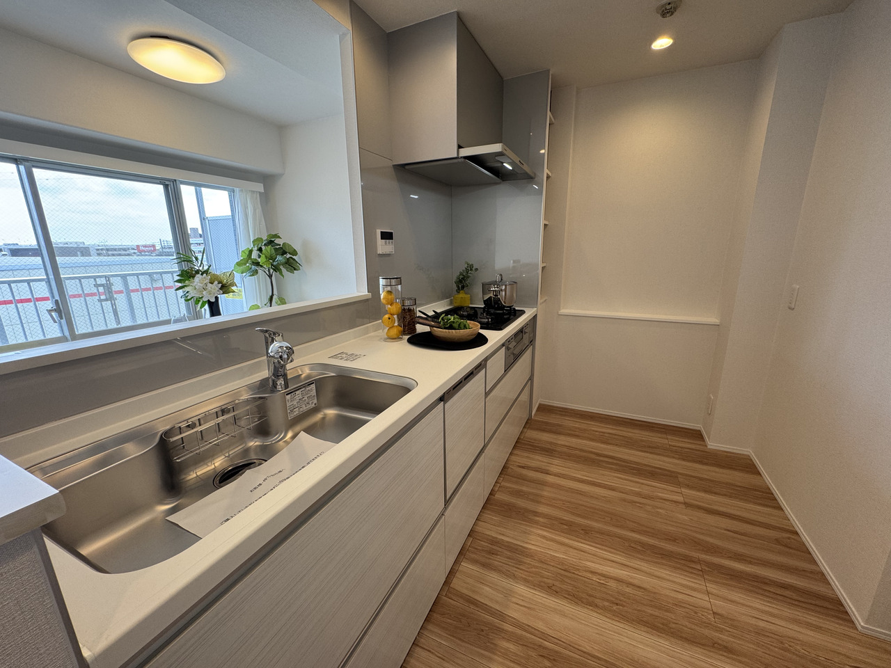 【キッチン】ビルトイン食器洗浄乾燥機・グリル・3口ガスコンロ付き。ストック収納として活用できる収納棚や、調味料などを置くことができるカウンターが設けられています。