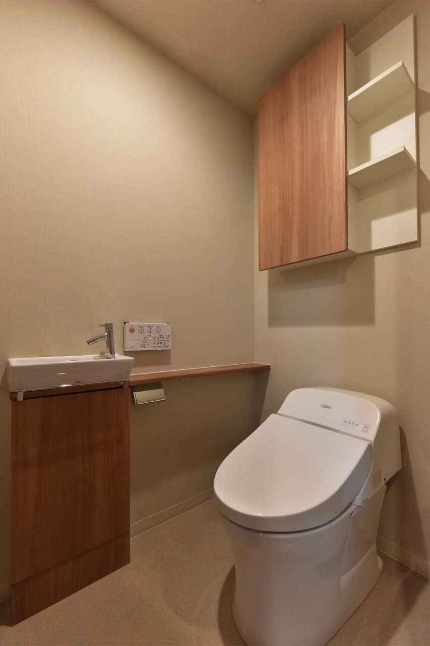 【トイレ】スタイリッシュなデザインが採用された、温水洗浄便座付きのトイレです。独立した手洗い器が設けられ、衛生面に配慮されています。カウンター部分には、お気に入りの小物を飾ることができます。