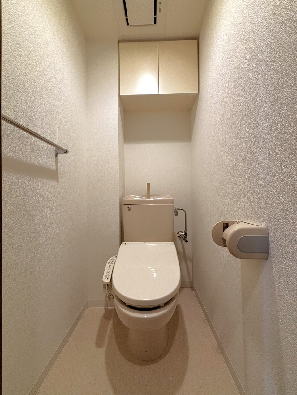 【トイレ】内装は、明るい色調で統一されています。上部に吊戸棚があり、予備のトイレットペーパーや掃除道具などを収納可能です。