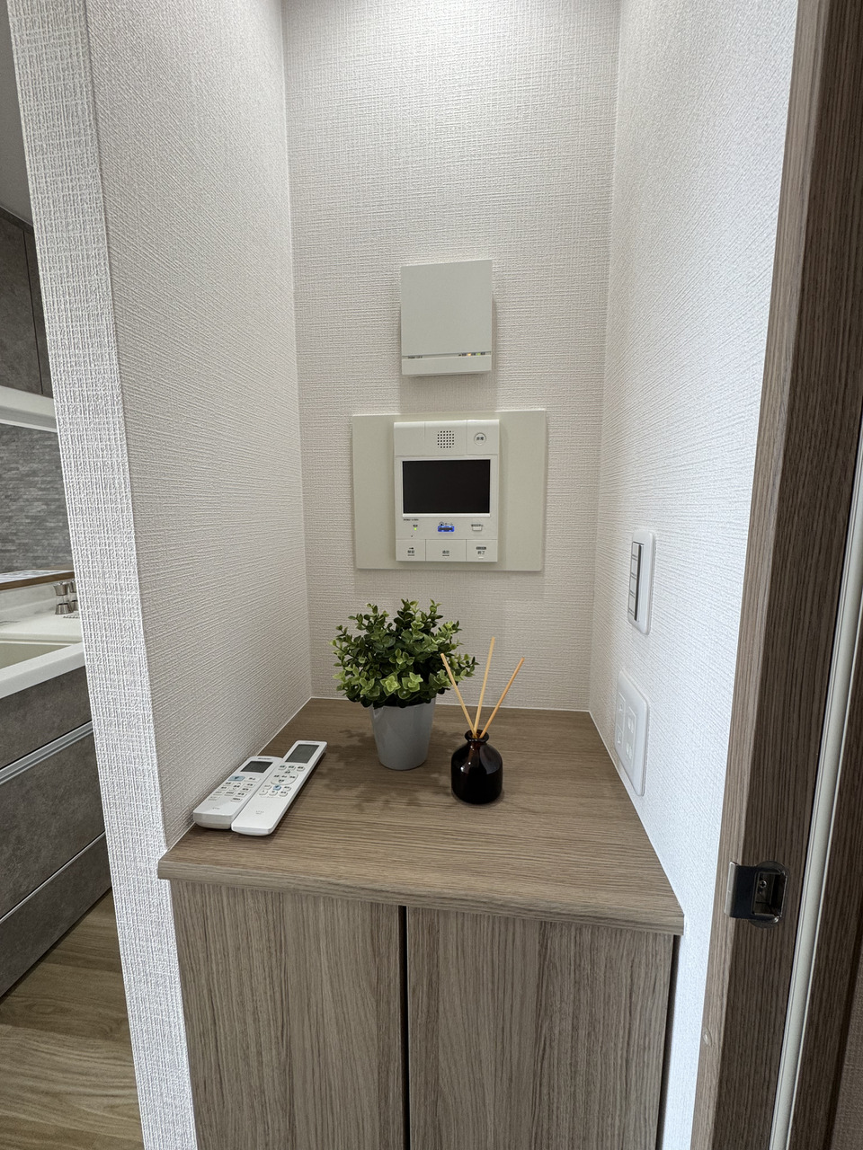 【LDK】LDKの入り口には作り付けの棚が設けられています。モニター付きインターホンなども壁面に設置されており、リモコンニッチのように自由に使える空間です。(2025年11月リフォーム済み)