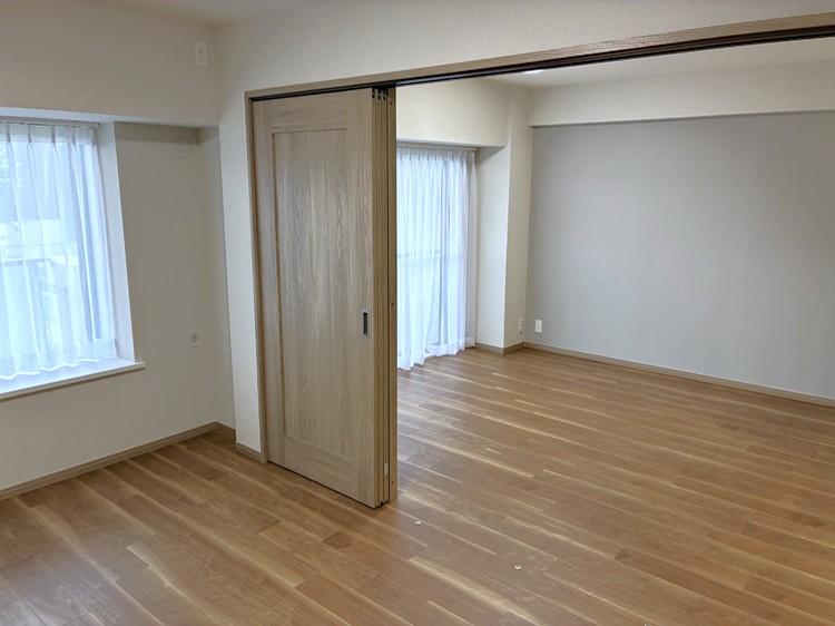 【洋室/約6.0帖】南向きのバルコニーに面しています。LDKに隣接し、引き戸を開放すると約18.6帖の空間としてフルフラットに繋がります。床に仕切りの溝が無いため、お掃除やお手入れがしやすいです。