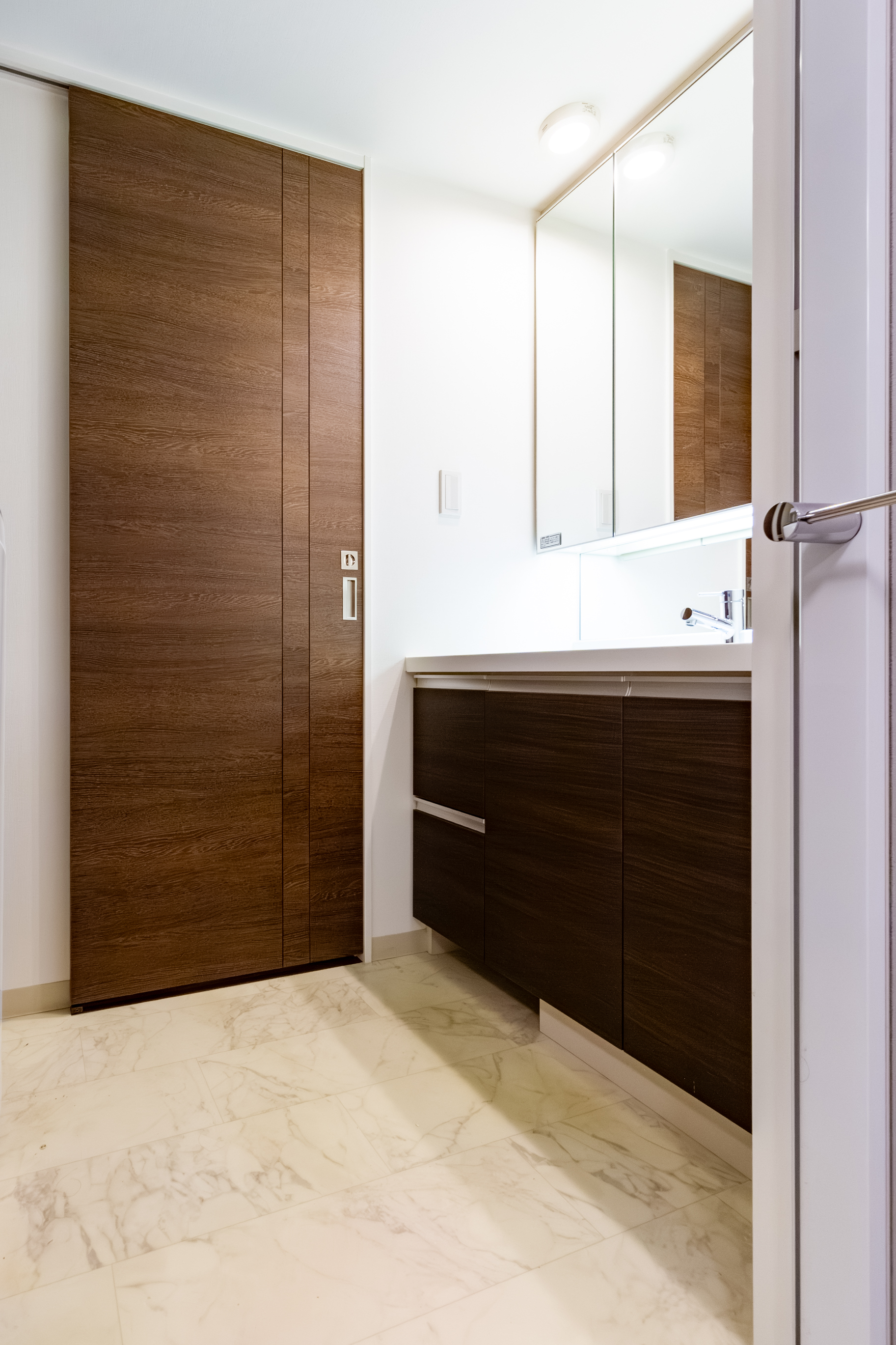 洗面所。洗面化粧台の向かい側には洗濯機置場とタオルや洗剤類を収納できるリネン庫があります。