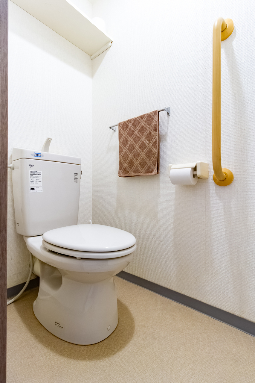 トイレにも手すりを設置しています。上部にはトイレットペーパーや小物を収納できる棚も設置されています。