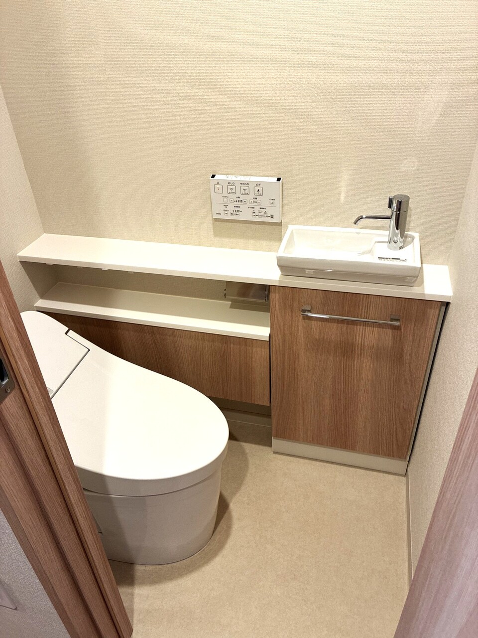 節水型タンクレストイレ。手洗いカウンターにはトイレットペーパーや掃除道具などの収納ができます
