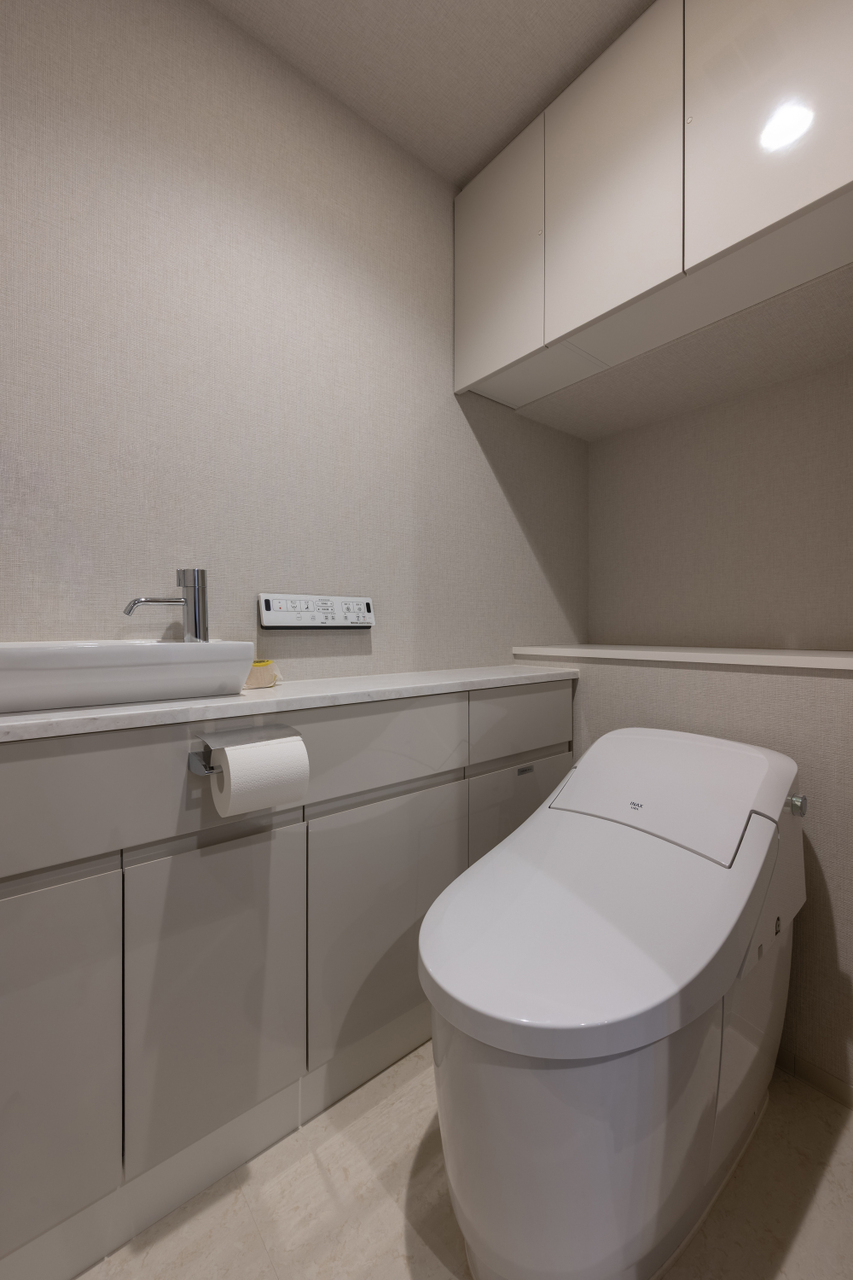 タンクレスのトイレです。手洗いカウンターの下や上部の吊戸棚があり、トイレットペーパーなどの小物も収納可能です。
