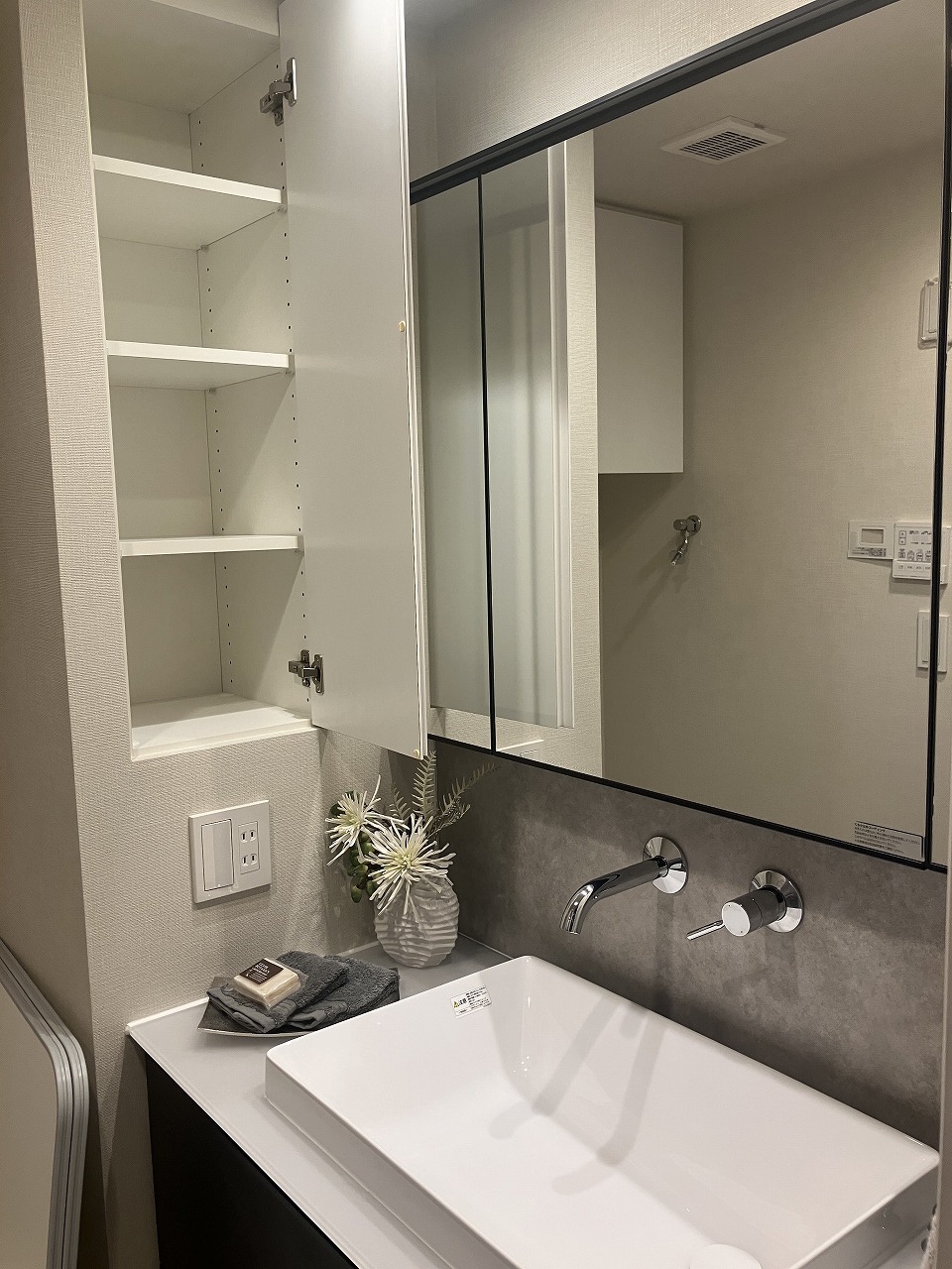 【洗面室】落ち着いた色合いでまとめられ、シックな印象の洗面化粧台。壁面に収納があり、化粧品や小物などを整理できます。※家具・調度品等は販売価格に含みません。