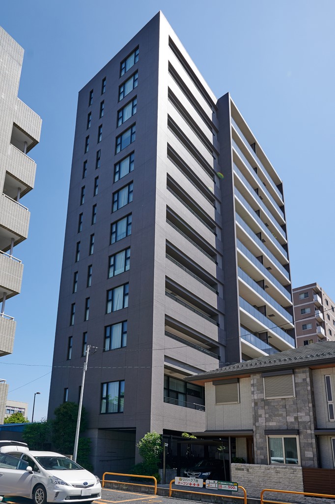 【現地外観写真】RC造・地上12階建てのマンション。外観はシックな色合いでまとめられており、街並みに映えるスタイリッシュな佇まいです。
