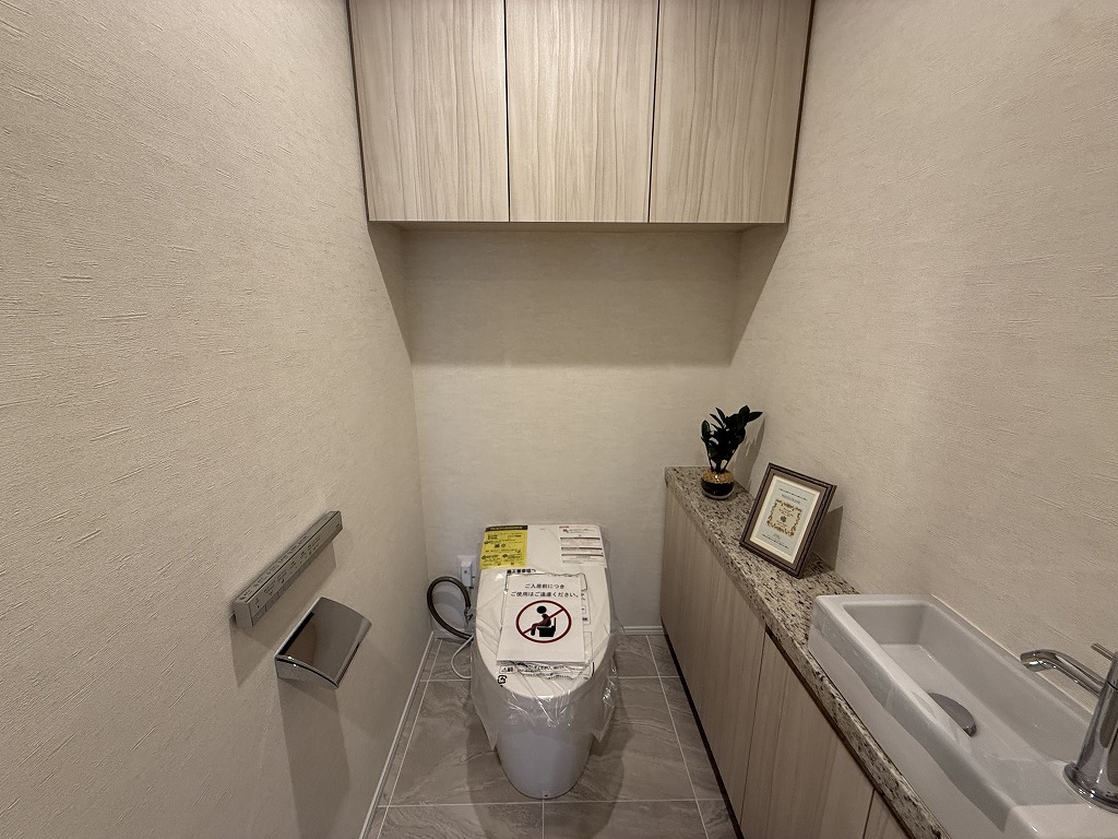 【トイレ】温水洗浄便座付きのトイレが採用されています。上部に収納棚があり、トイレットペーパーや掃除用品を収納することができます。