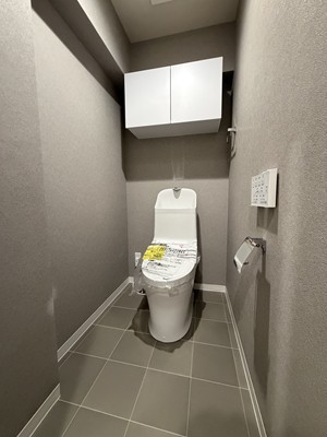 【トイレ】毎日清潔に使用できる温水洗浄便座付き。壁にリモコンが備え付けられており、操作がしやすいです。トイレットペーパーなどの保管に便利な吊戸棚付き。
