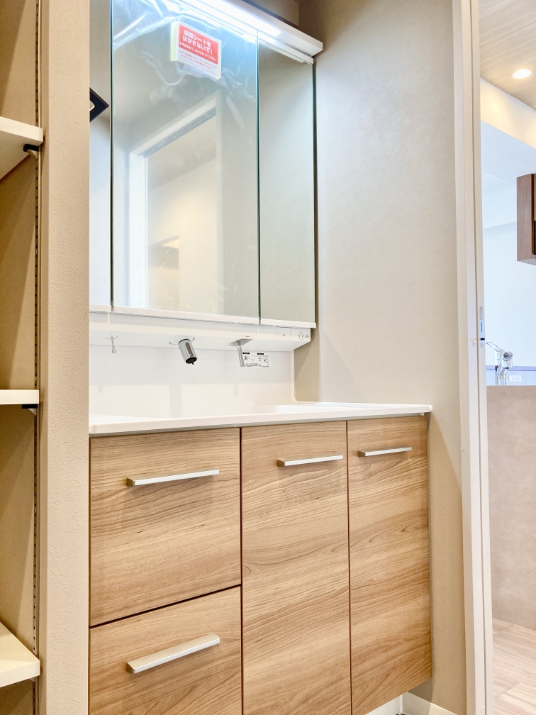 【洗面化粧台】三面鏡付きの洗面化粧台です。鏡裏やボウル下に収納スペースが備わっているため、散らかりがちな洗面小物やストック類もすっきりと整理できます。