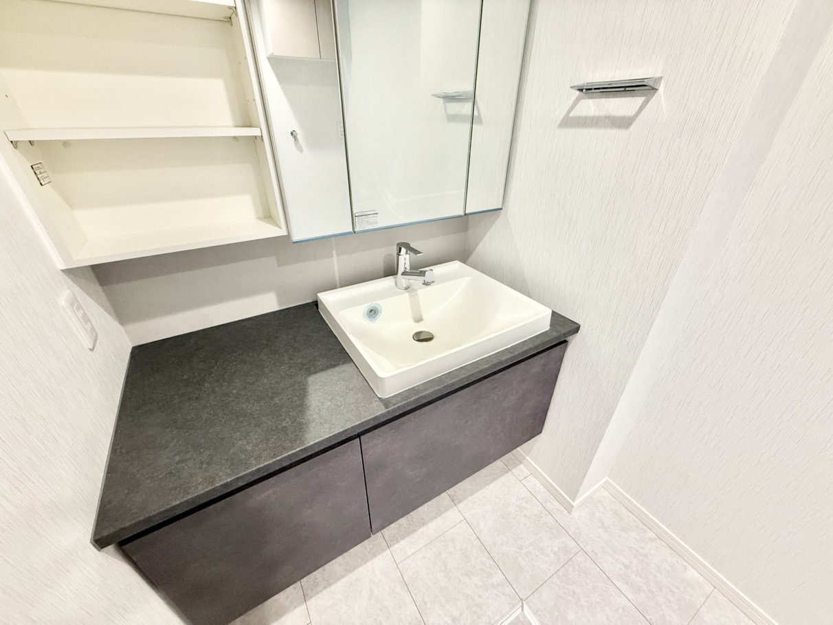 【洗面室】シックな色合いの洗面化粧台が備わっています。豊富な収納と広いカウンターが快適な身支度をサポートします。