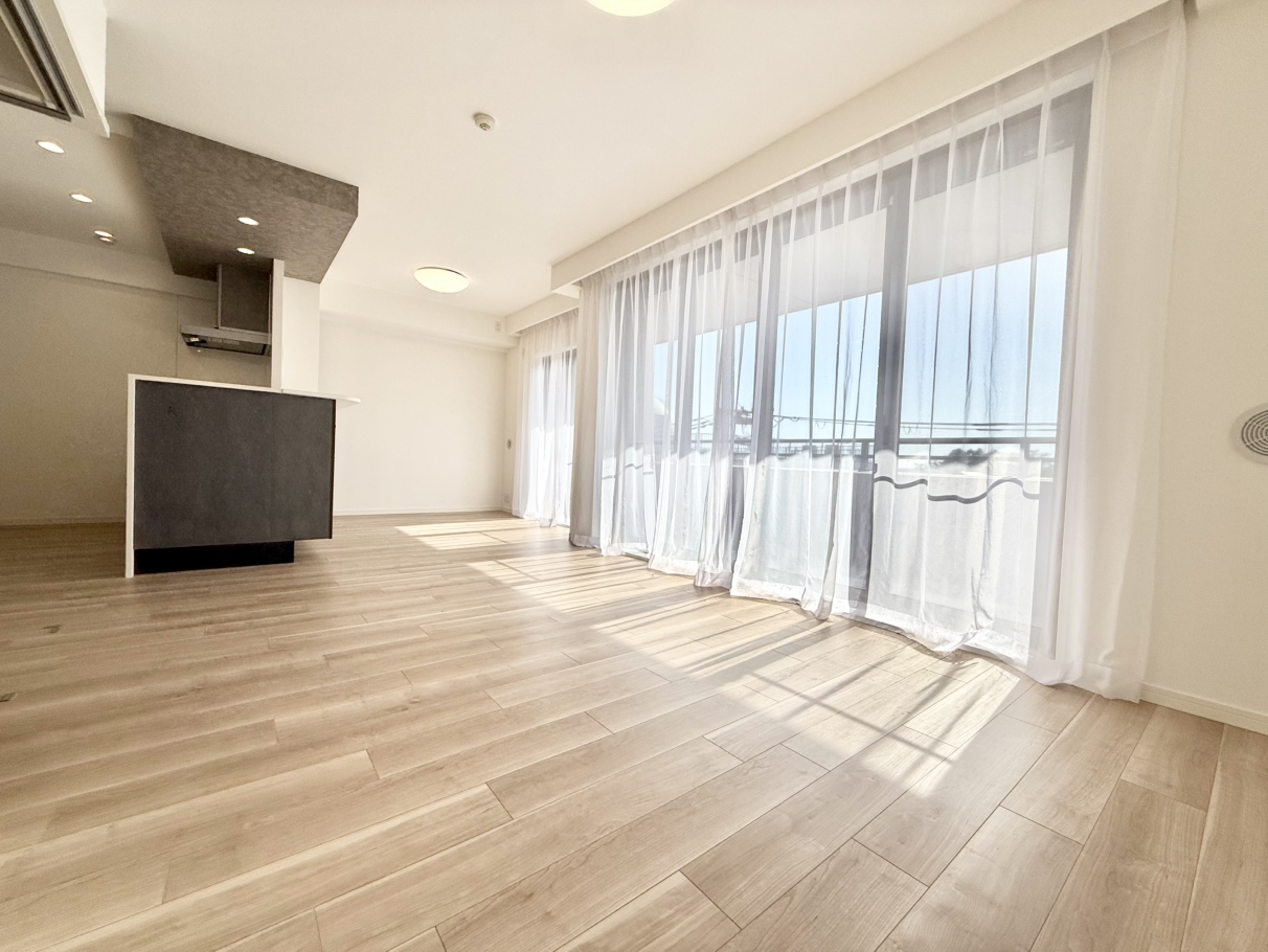 【LDK】ご家族が集うLDKは約16.6帖の広さ。西側の窓からあたたかな陽光が注ぐ、心地よい空間です。キッチン上部には下がり天井が採用され、空間にアクセントを添えています。