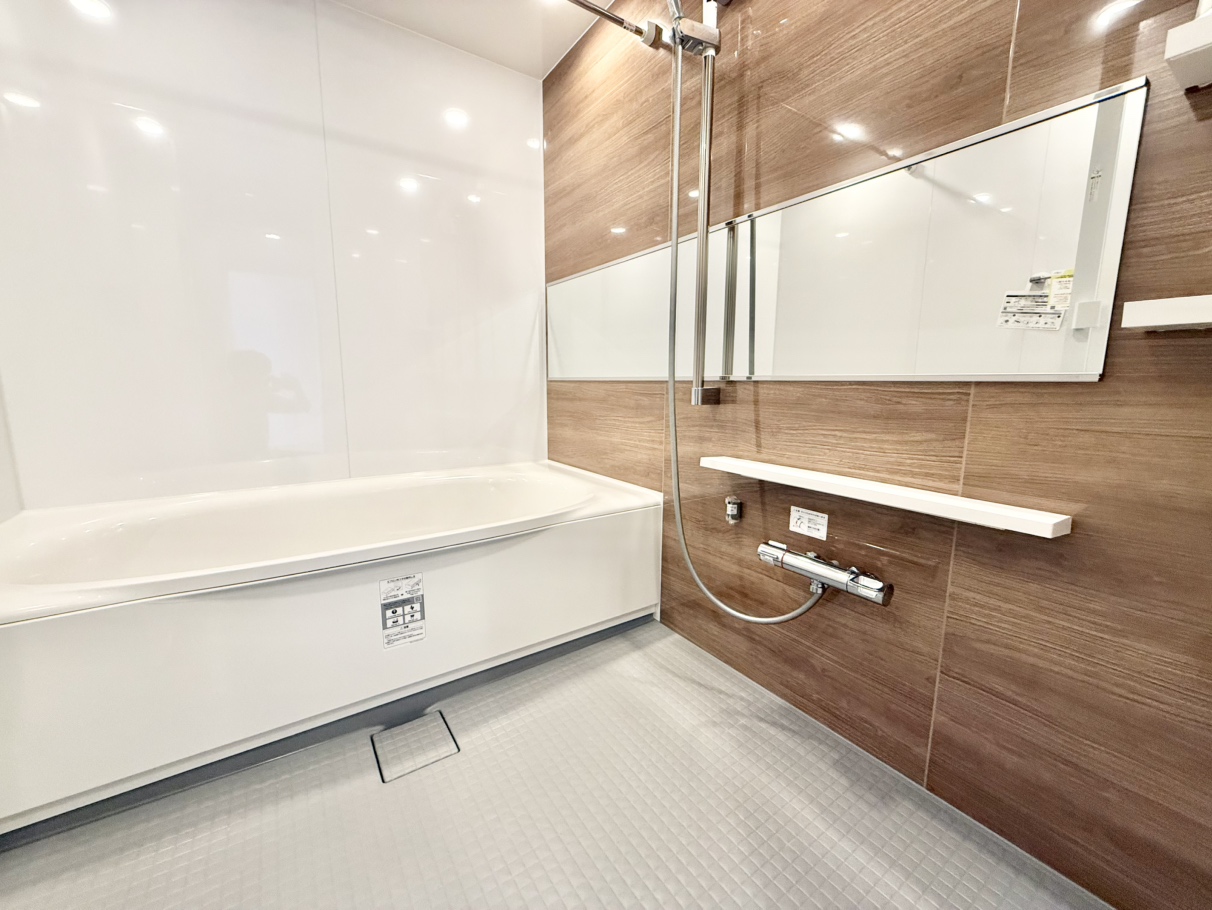 【浴室】1620サイズのゆとりある浴室。木目調のアクセントパネルが施され、温かみがあります。浴室乾燥機付きで季節や天候を問わずに洗濯物を乾かすことが可能。