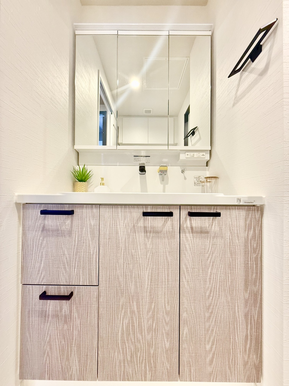 【洗面室】洗面室には三面鏡付きの洗面化粧台が備わっています。三面鏡の裏・洗面ボウル下に収納があり、日用品や洗面用具、化粧品などを整理できます。