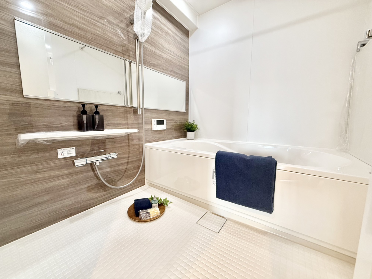 【浴室】美しい木目調のアクセントパネルが採用された浴室。横長のワイドミラーは浴槽に浸かりながらパックやマッサージなどをする際に便利です。