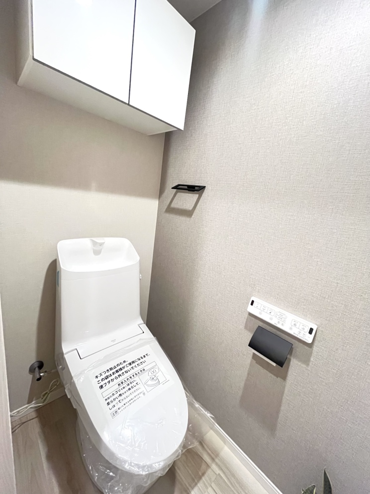 【トイレ】毎日快適にお使いいただける、温水洗浄便座付きのトイレ。扉付きの吊戸棚があり、トイレットペーパーや掃除用品などを収納可能です。