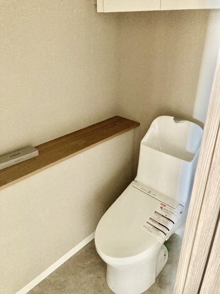 【トイレ】清潔感あふれるホワイトのトイレです。手洗いタンク付きで、使用後すぐに手を洗うことができます。カウンター部分にはお気に入りの小物を飾り、お好みの空間づくりを楽しめます。