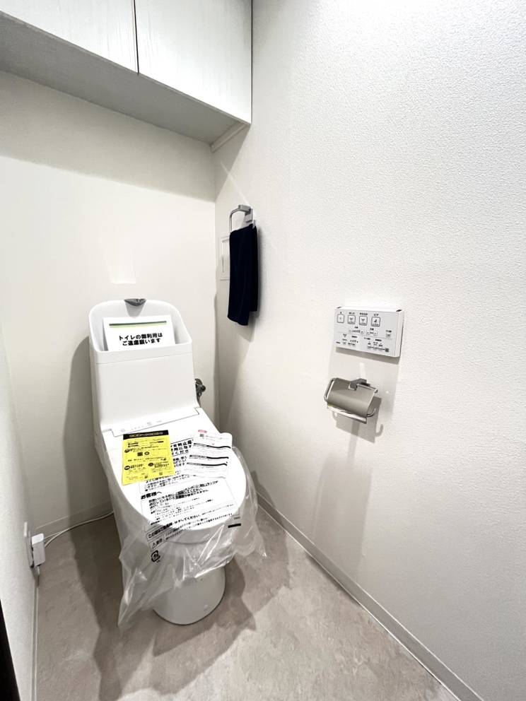 【トイレ】清潔感ある色合いのトイレです。背面には収納棚が設置されているので、トイレットペーパーや掃除用具などを収納できます。