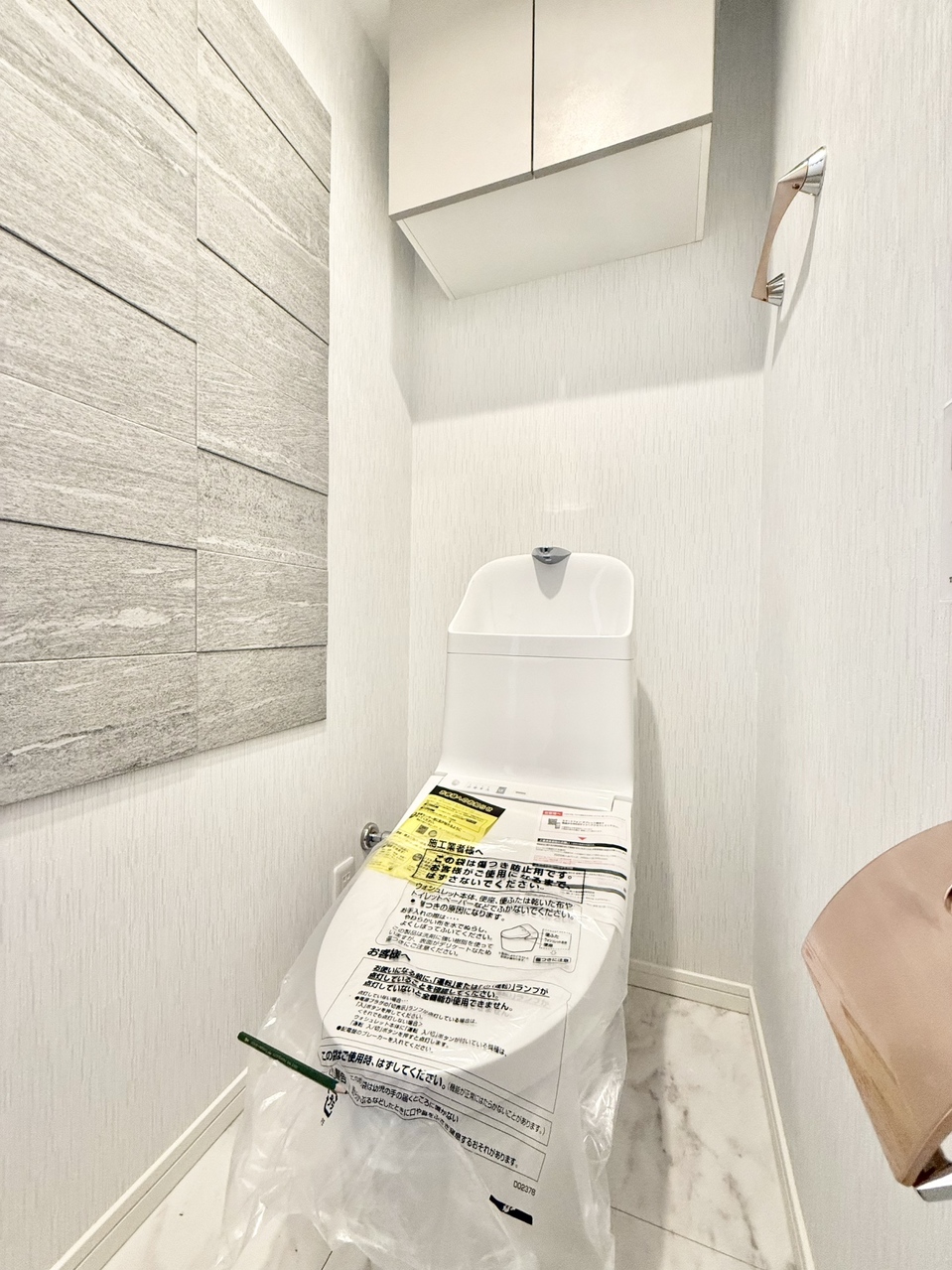 【トイレ】清潔に利用できる温水洗浄機能付きトイレです。上部には収納棚が設置されており、トイレットペーパーや掃除用品を収納することができます。