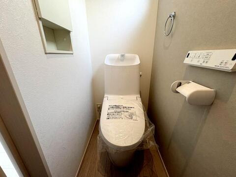 温水洗浄便座付きの清潔感あふれるトイレ。上部にはトイレットペーパー等をしまえる収納棚付き。