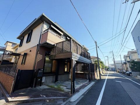 青空に映えるツートン外観とウッドフェンス付きの広々バルコニー。1階にはガレージスペースを備え、開放的な住環境でゆとりある暮らしを叶えます。