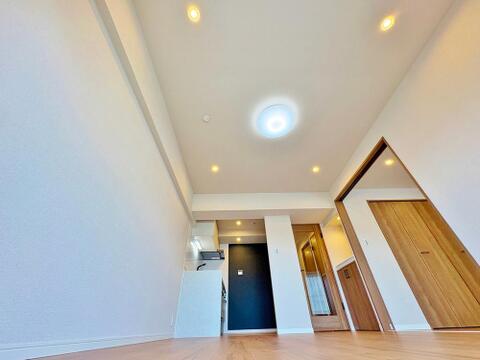 白壁に映える木目調の建具が美しい、リビングから見た風景。折り上げ天井に配された照明が空間に奥行きと上品なニュアンスをプラスし、くつろぎのひとときを演出します。