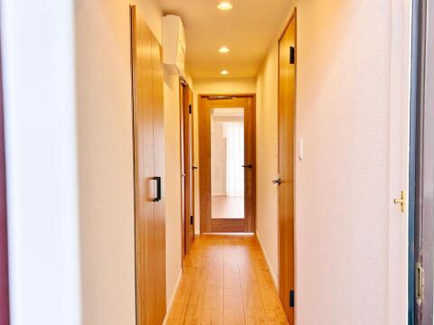 新規内装リフォームされた廊下です。木目調の建具が暖かみのある雰囲気を醸し出しており、毎日の帰宅時にほっとさせてくれる空間がここにはあります。