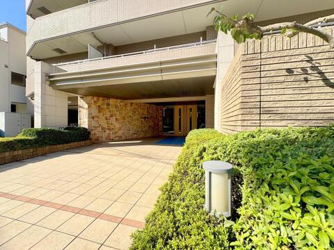 鮮やかな緑の植栽に彩られた、開放感あふれる石畳のアプローチ。太陽の光を豊かに受け止めながら、重厚な意匠が邸宅としての気品を演出します。住まう方を温かく包み込む、落ち着きと寛ぎの入り口です。